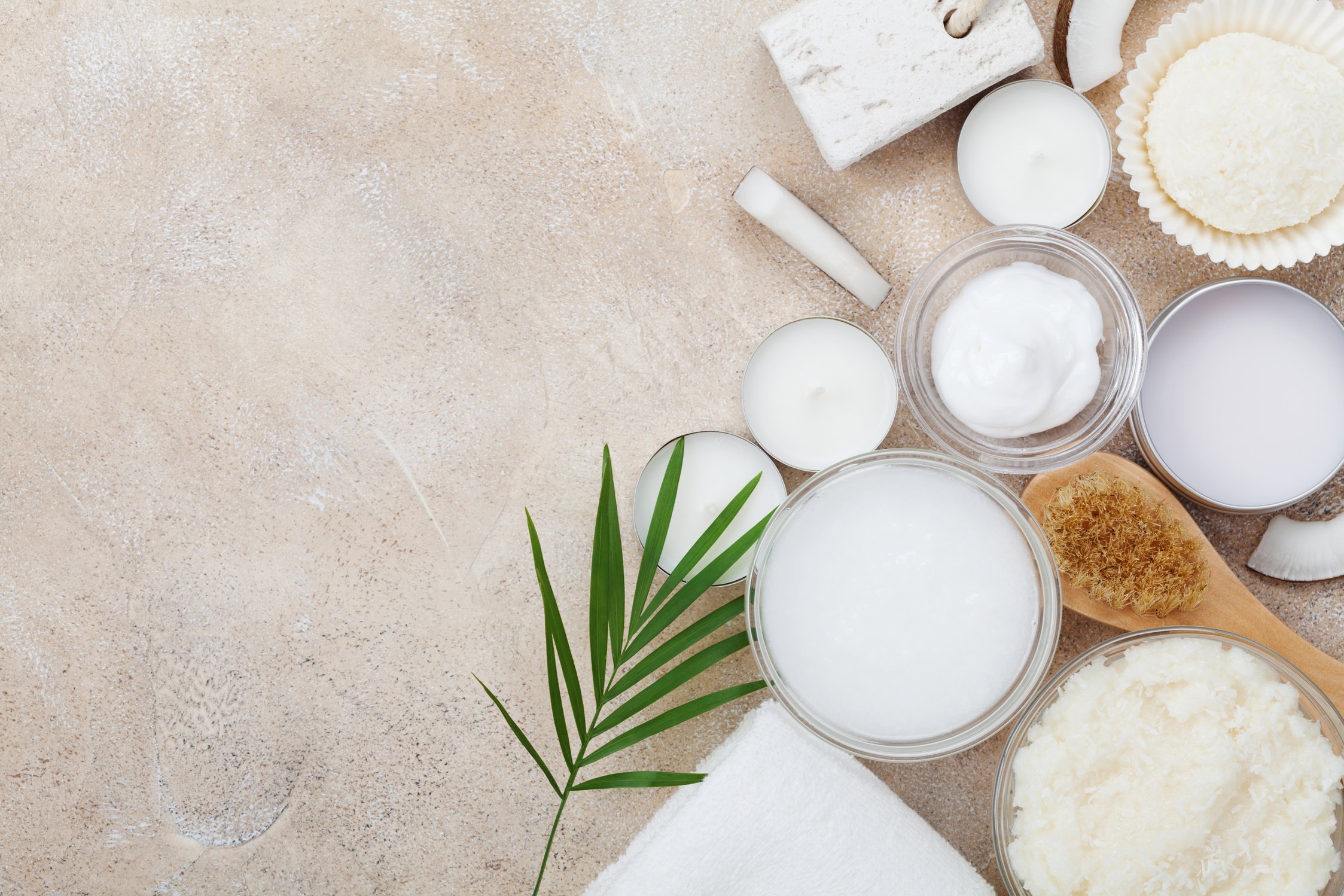 Spa setting from body care and beauty treatment. Organic coconut scrub, oil and cream on stone table top view. Flat lay.